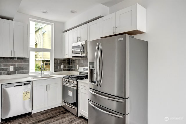 kitchen featuring appliances with stainless steel finishes, tasteful backsplash, sink, white cabinets, and dark hardwood / wood-style floors