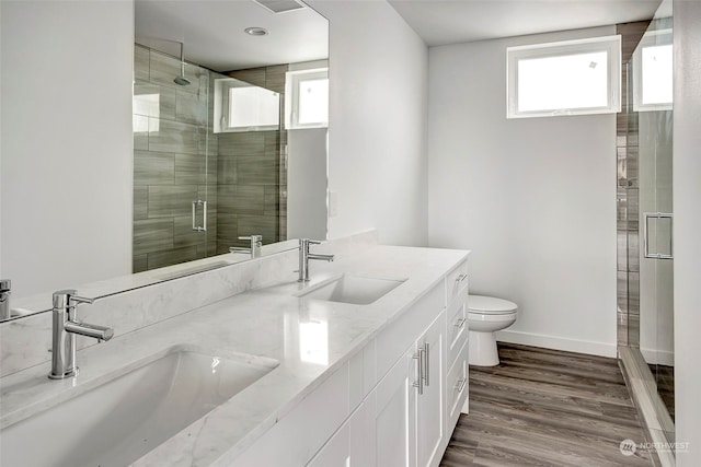 bathroom featuring wood-type flooring, vanity, toilet, and walk in shower