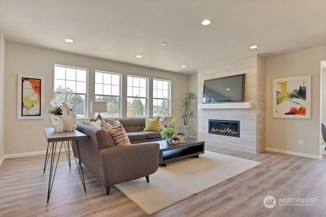 living room with a large fireplace, a healthy amount of sunlight, and light hardwood / wood-style floors