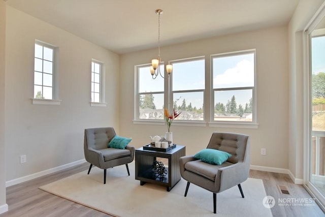 sitting room with a chandelier, light hardwood / wood-style flooring, and a healthy amount of sunlight