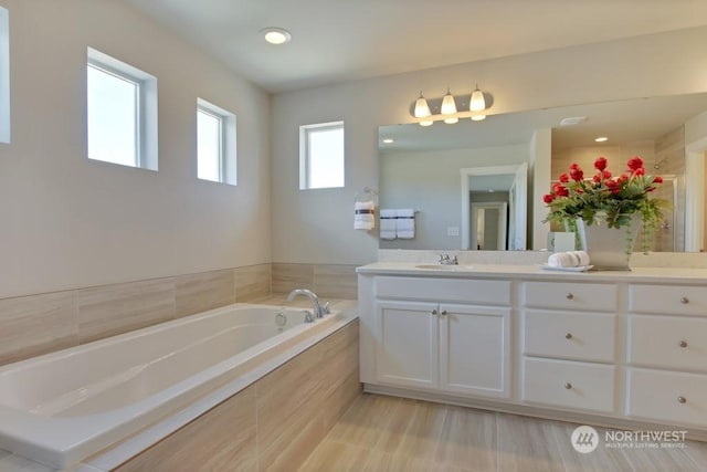 bathroom with vanity and tiled tub