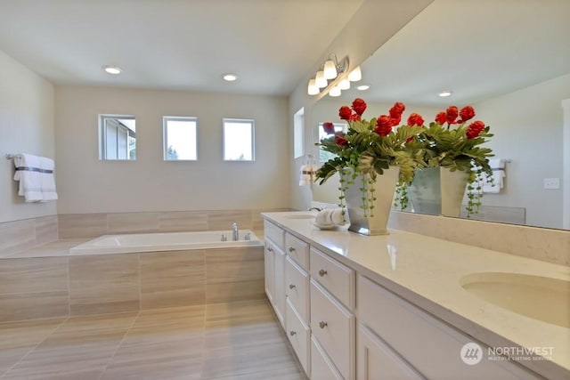 bathroom with tile patterned flooring, vanity, and tiled tub