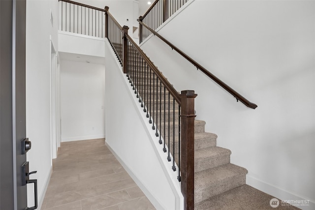 stairway with baseboards and a towering ceiling