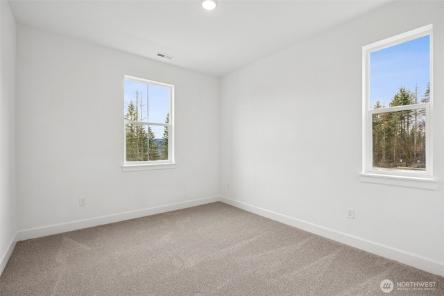 empty room with carpet flooring, visible vents, and baseboards