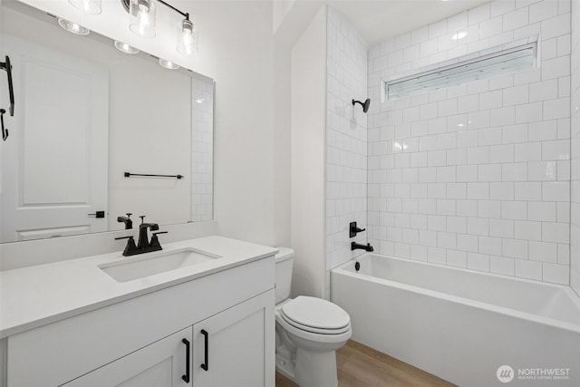 bathroom with toilet, vanity,  shower combination, and wood finished floors