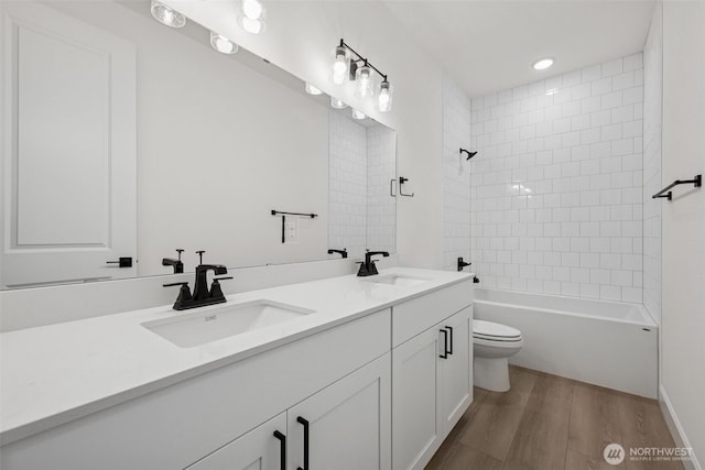 full bathroom featuring a sink, toilet, wood finished floors, and double vanity