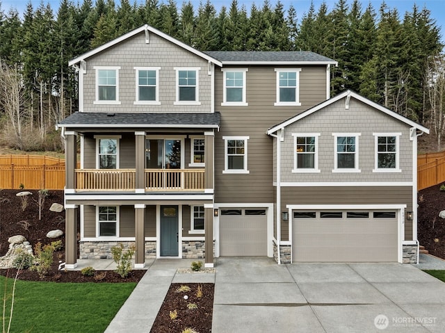 view of front facade with a balcony, fence, driveway, a garage, and stone siding