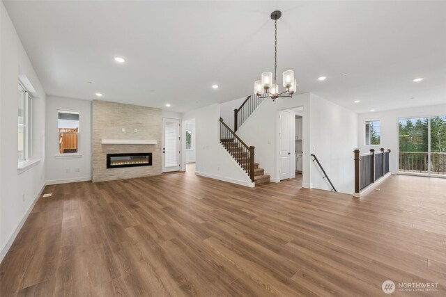 unfurnished living room featuring a large fireplace, baseboards, stairs, recessed lighting, and wood finished floors