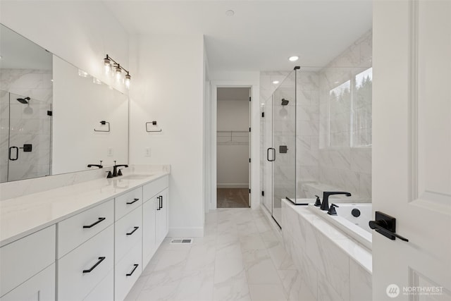 bathroom with visible vents, a shower stall, a walk in closet, a garden tub, and marble finish floor