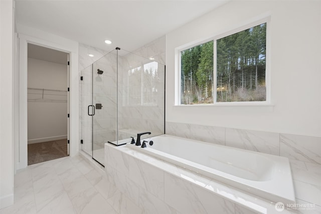 bathroom with marble finish floor, a stall shower, a spacious closet, and a bath