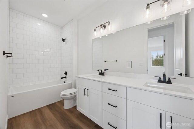 full bath with double vanity, toilet, wood finished floors, and a sink