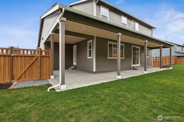 rear view of house with a gate, a patio, a yard, and fence