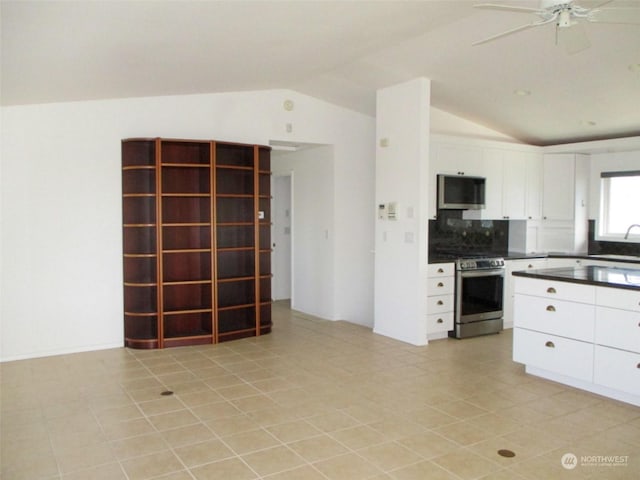kitchen featuring lofted ceiling, white cabinets, ceiling fan, appliances with stainless steel finishes, and tasteful backsplash