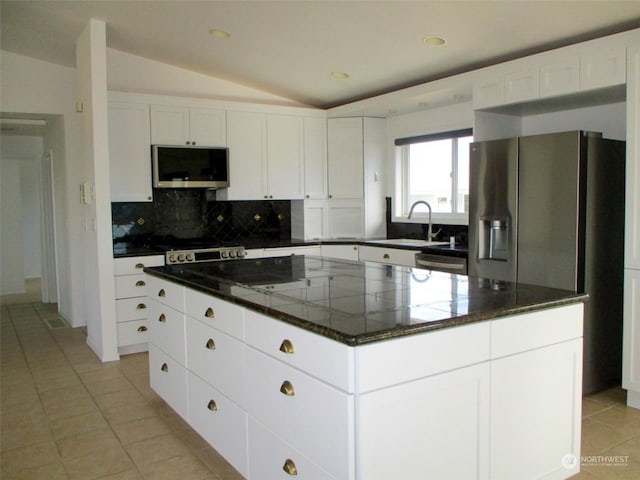 kitchen with a kitchen island, appliances with stainless steel finishes, and vaulted ceiling