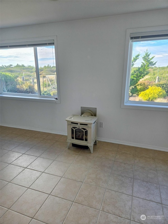 tiled spare room featuring a wood stove