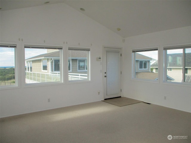 spare room featuring carpet floors, a healthy amount of sunlight, and vaulted ceiling