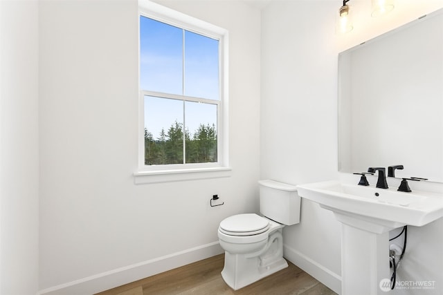 bathroom featuring a sink, toilet, baseboards, and wood finished floors