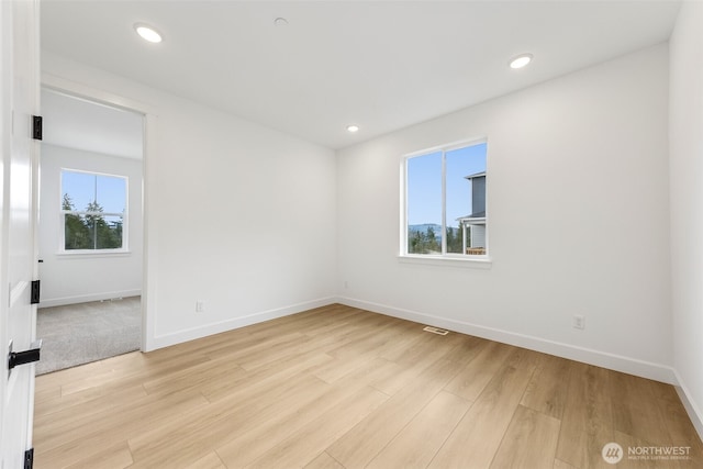 empty room with light wood-style flooring, a healthy amount of sunlight, and visible vents