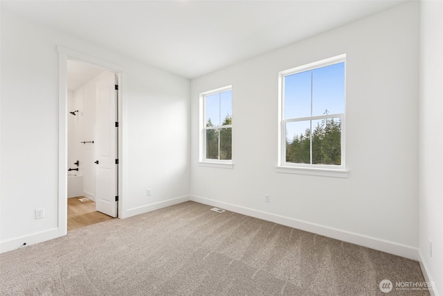 carpeted spare room featuring visible vents and baseboards