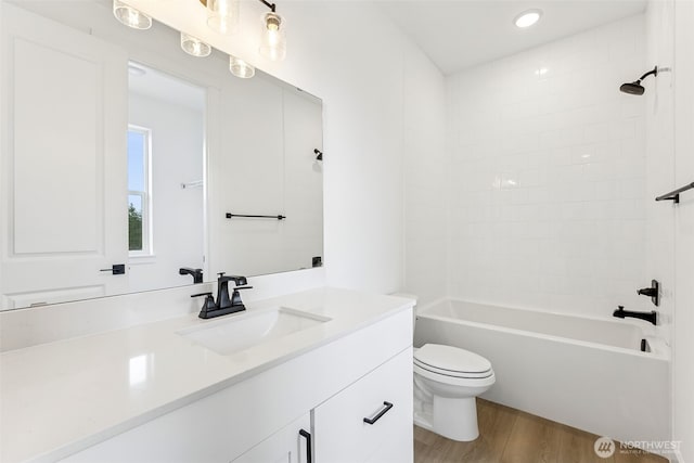 bathroom with vanity, washtub / shower combination, toilet, and wood finished floors