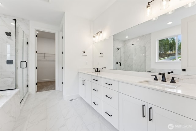 full bath with a marble finish shower, marble finish floor, a spacious closet, and a sink