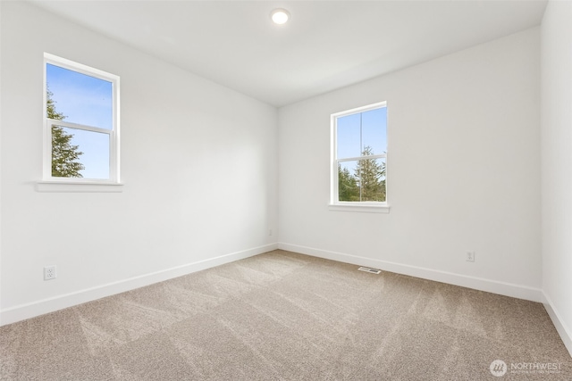 spare room with carpet flooring, baseboards, and visible vents