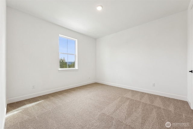 carpeted spare room featuring baseboards