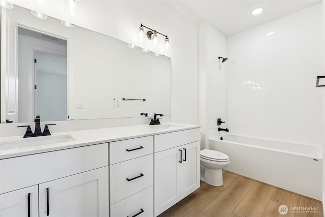 bathroom with double vanity, toilet, wood finished floors, and a sink