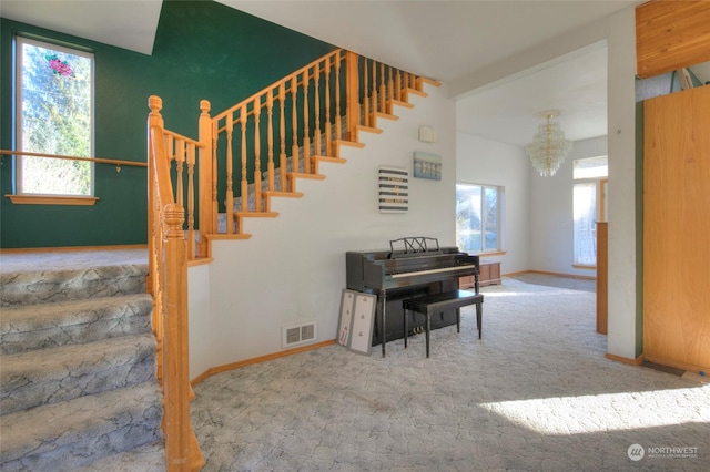 stairs with carpet floors and a notable chandelier