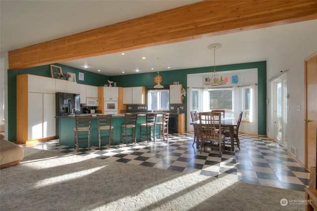 kitchen featuring pendant lighting, white cabinetry, and black refrigerator with ice dispenser