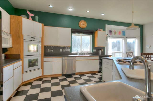 kitchen featuring white appliances, white cabinets, sink, decorative backsplash, and decorative light fixtures