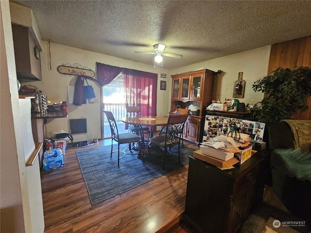 dining area with a textured ceiling, ceiling fan, and dark wood-type flooring