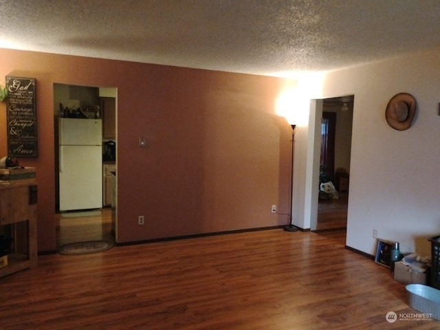 empty room with dark hardwood / wood-style floors and a textured ceiling