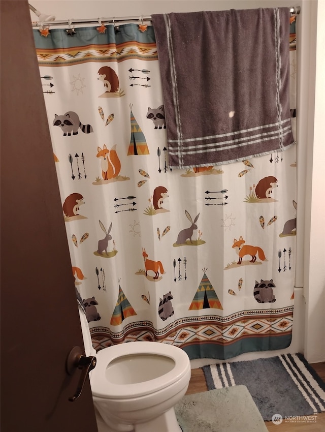 bathroom featuring hardwood / wood-style floors, curtained shower, and toilet