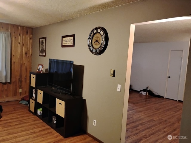 living room featuring wood walls, wood-type flooring, and a textured ceiling