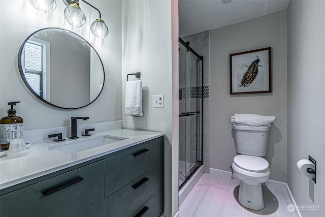 bathroom featuring tile patterned floors, vanity, a shower with shower door, and toilet