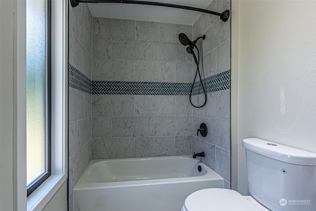 bathroom with tiled shower / bath combo and toilet