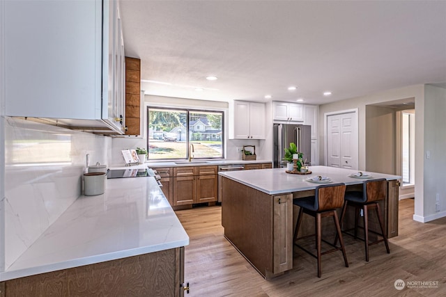 kitchen featuring a breakfast bar area, stainless steel fridge, a kitchen island, and light hardwood / wood-style floors