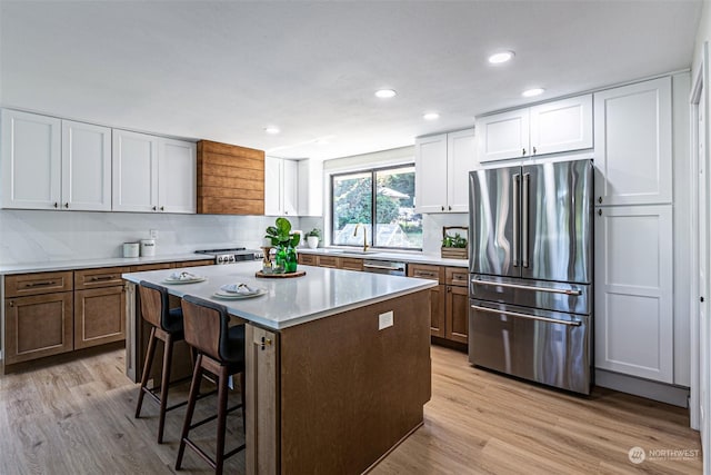 kitchen with light hardwood / wood-style flooring, white cabinets, stainless steel appliances, and a kitchen island