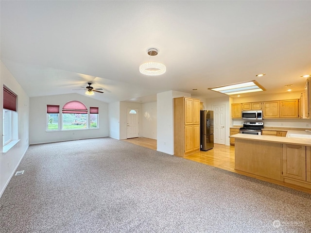 kitchen featuring light carpet, sink, vaulted ceiling, appliances with stainless steel finishes, and kitchen peninsula