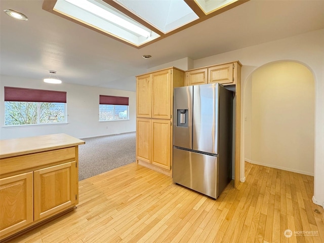 kitchen featuring stainless steel fridge with ice dispenser, light brown cabinetry, and light hardwood / wood-style flooring