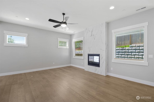 unfurnished living room featuring ceiling fan, a fireplace, a healthy amount of sunlight, and hardwood / wood-style flooring