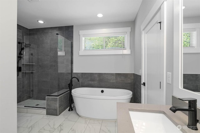 bathroom featuring a wealth of natural light, vanity, tile walls, and plus walk in shower