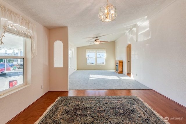 unfurnished living room featuring wood-type flooring, ceiling fan with notable chandelier, a textured ceiling, and lofted ceiling