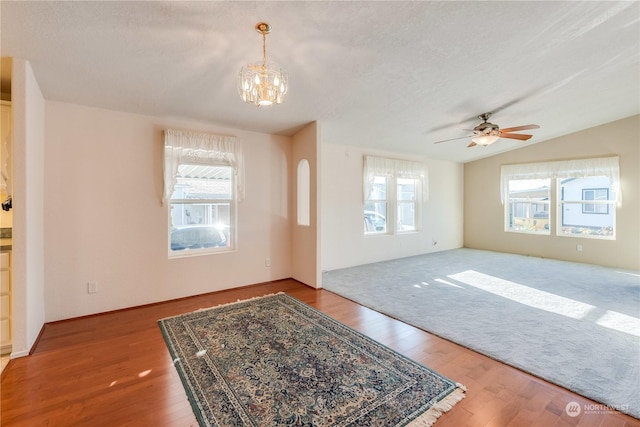 interior space featuring a healthy amount of sunlight, wood-type flooring, a textured ceiling, and vaulted ceiling