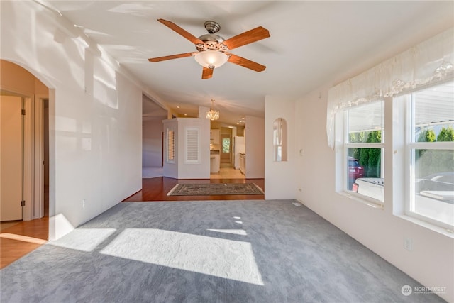 empty room with hardwood / wood-style flooring, ceiling fan with notable chandelier, and lofted ceiling