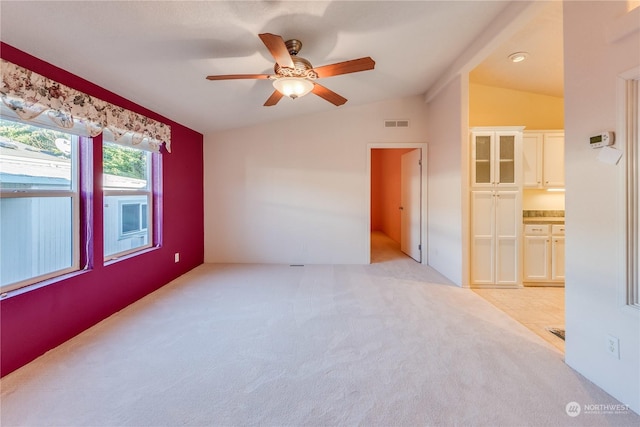 carpeted spare room with ceiling fan and vaulted ceiling