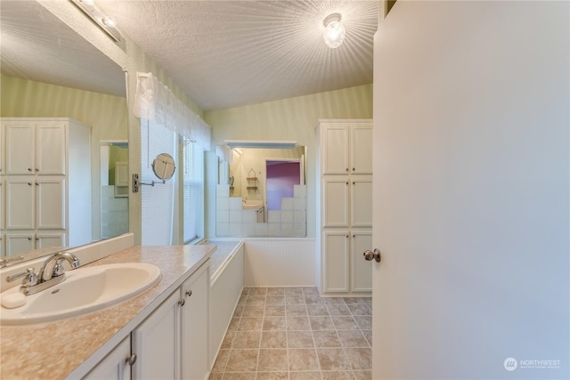 bathroom with a textured ceiling, tile patterned flooring, vanity, and vaulted ceiling