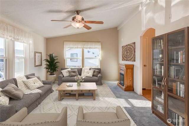 living room with ceiling fan, a healthy amount of sunlight, light colored carpet, and vaulted ceiling