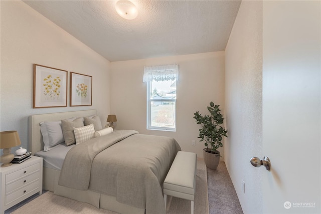 bedroom with a textured ceiling, light carpet, and vaulted ceiling